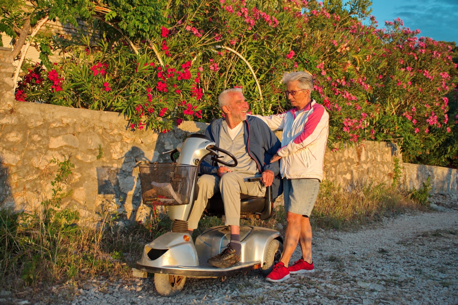 Senior couple walking along promenade by the Adriatic sea - senior citizen in mobility scooter
